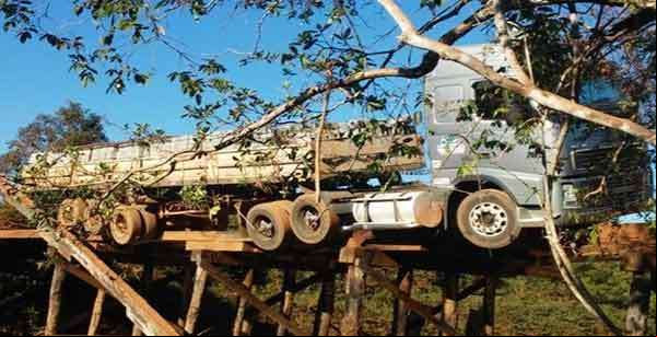 Carreta fica pendurada em ponte após estrutura ceder, carga teve que ser jogada dentro de rio